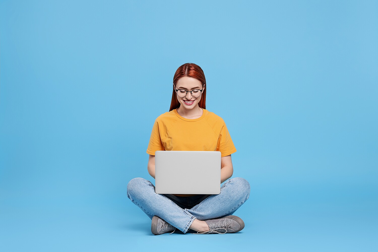 Smiling,Young,Woman,Working,With,Laptop,On,Light,Blue,Background